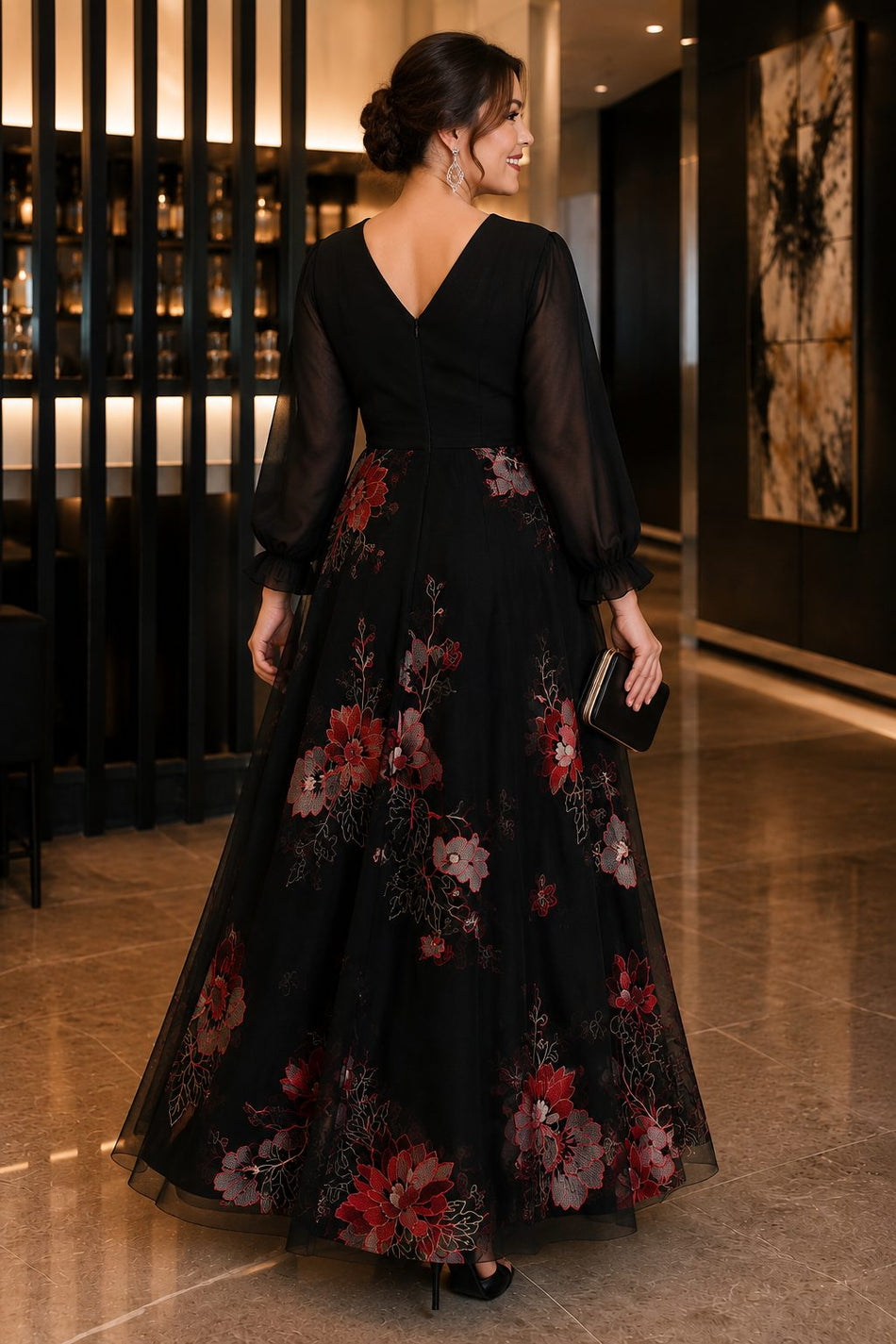 Back view of a plus size black floral evening dress featuring sheer long sleeves, V-back neckline and flowing embroidered A-line skirt.