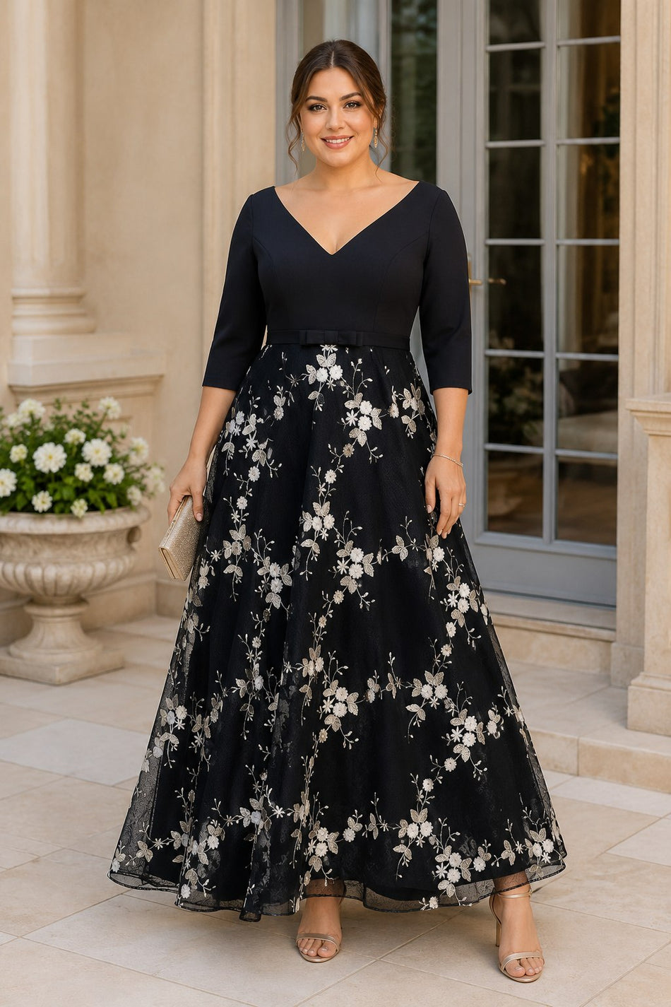 Front view of a plus size black formal dress with three-quarter sleeves, V-neckline and floral embroidered A-line skirt.