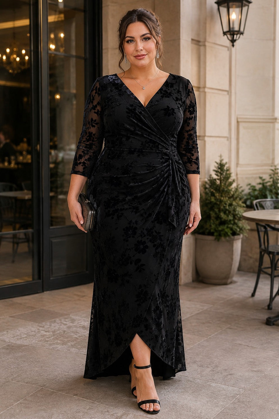 Plus size woman wearing a black floral maxi formal dress with V neckline, sheer three-quarter sleeves and draped front skirt.