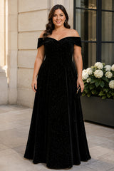 Plus size woman wearing a black off-shoulder evening dress with crossover neckline, defined waist and full-length A-line skirt.