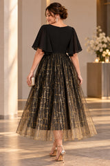 Back view of a plus size black and gold midi cocktail dress with flutter sleeves and a full metallic patterned skirt.