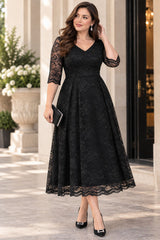 Plus size woman wearing a black lace midi cocktail dress with V neckline, sheer elbow-length sleeves and full A-line skirt.