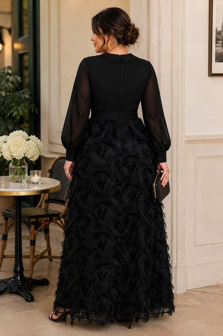 Back view of a plus size black evening maxi dress with long sheer sleeves, defined waistband and full textured A-line skirt.