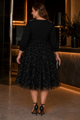 Back view of a plus size black midi cocktail dress with three-quarter sleeves, defined waistband and full sparkling patterned skirt.