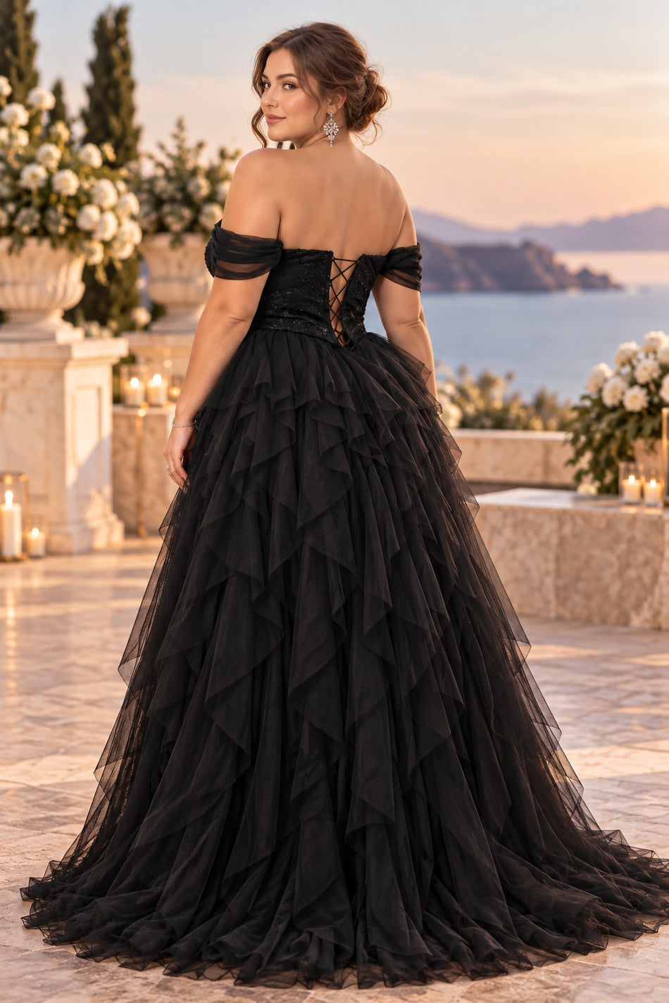Back view of a black plus size off shoulder tulle formal gown with a fitted bodice and full cascading layered skirt.