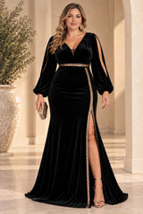 Plus size woman wearing a floor-length black velvet evening dress with deep V neckline, split long sleeves, gold-toned waist detail and front slit.