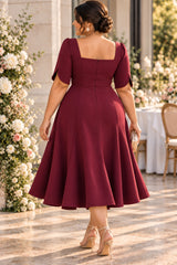 Back view of plus size burgundy A-line midi cocktail dress with petal sleeves and full skirt.
