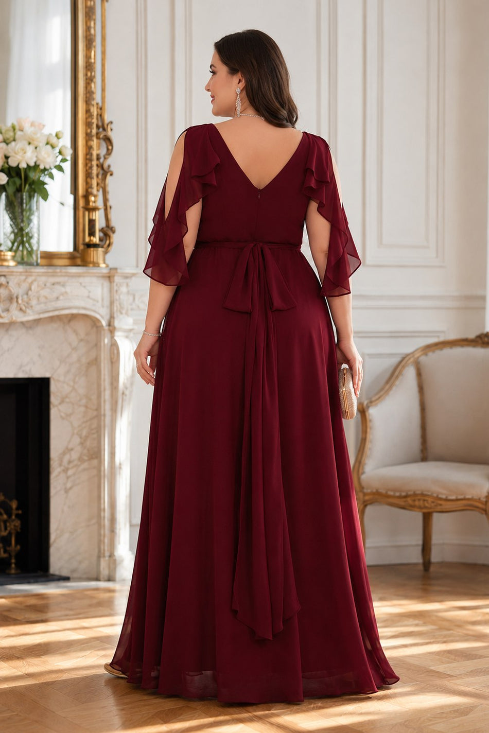 Back view of a plus size burgundy formal dress featuring a V-back neckline, flutter sleeves and waist tie.