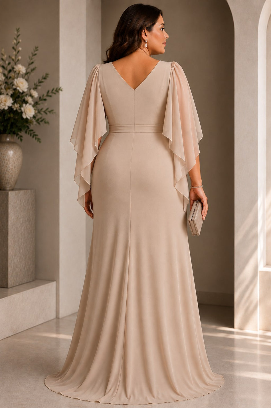 Back view of a plus size woman wearing a champagne wrap evening dress with V neckline, cape sleeves and cascading front drape.