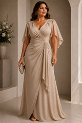 Plus size woman wearing a champagne wrap evening dress with V neckline, cape sleeves and cascading front drape.