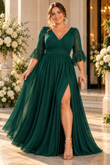 Plus size woman wearing a emerald green chiffon formal maxi dress with wrap V-neck, 3/4 flutter sleeves and flowing skirt.