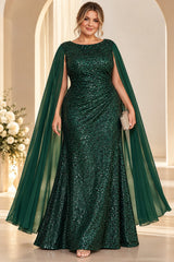 Plus size woman wearing an emerald green sequin evening gown with diagonal waist draping and long flowing cape sleeves.