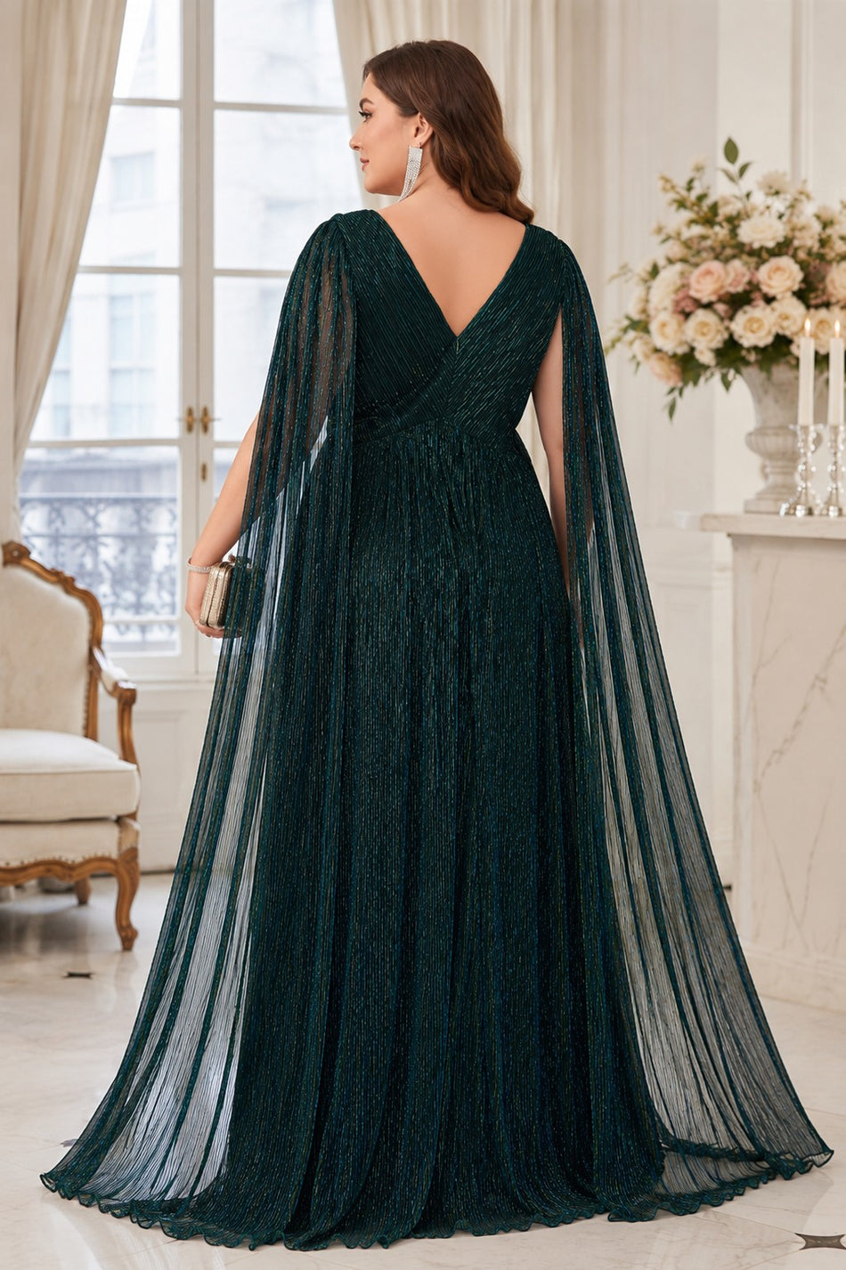 Back view of plus size emerald green Grecian evening dress with deep V-back, defined waist, flowing skirt and long sheer cape sleeves.