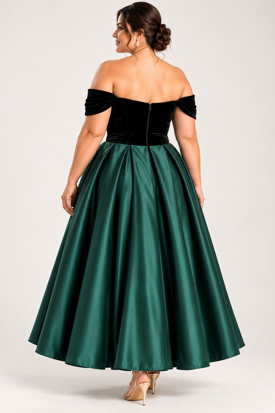 Back view of a plus size woman wearing an emerald green midi dress with a black off-shoulder bodice and full A-line skirt.
