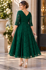 Back view of an emerald green floral lace midi dress showing the V-back neckline, defined waist and flared skirt.