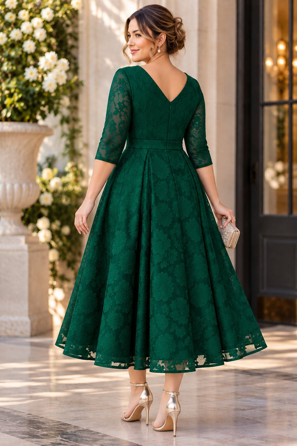 Back view of an emerald green floral lace midi dress showing the V-back neckline, defined waist and flared skirt.