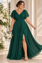 Plus size woman wearing an emerald green wrap-style maxi formal dress with V neckline, flutter sleeves and cascading front drape.
