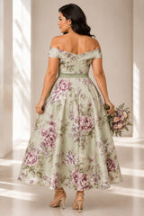 back view of plus size woman wearing a sage green floral off shoulder A-line midi wedding guest dress with a defined waist.