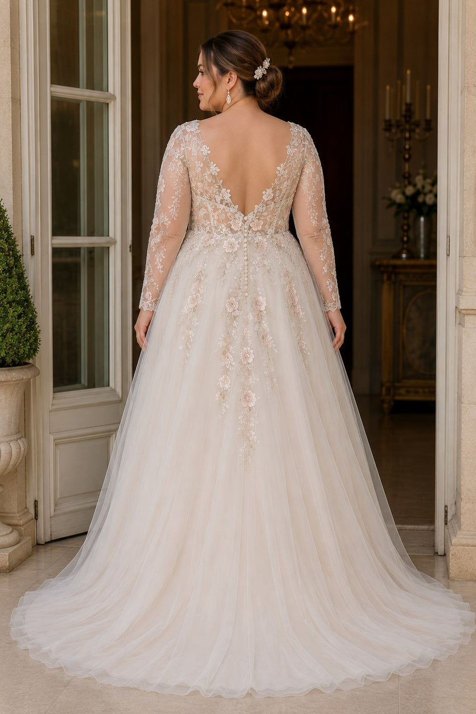 Back view of a plus size floral wedding dress featuring a V-back, floral embroidery, illusion sleeves and flowing full-length skirt.