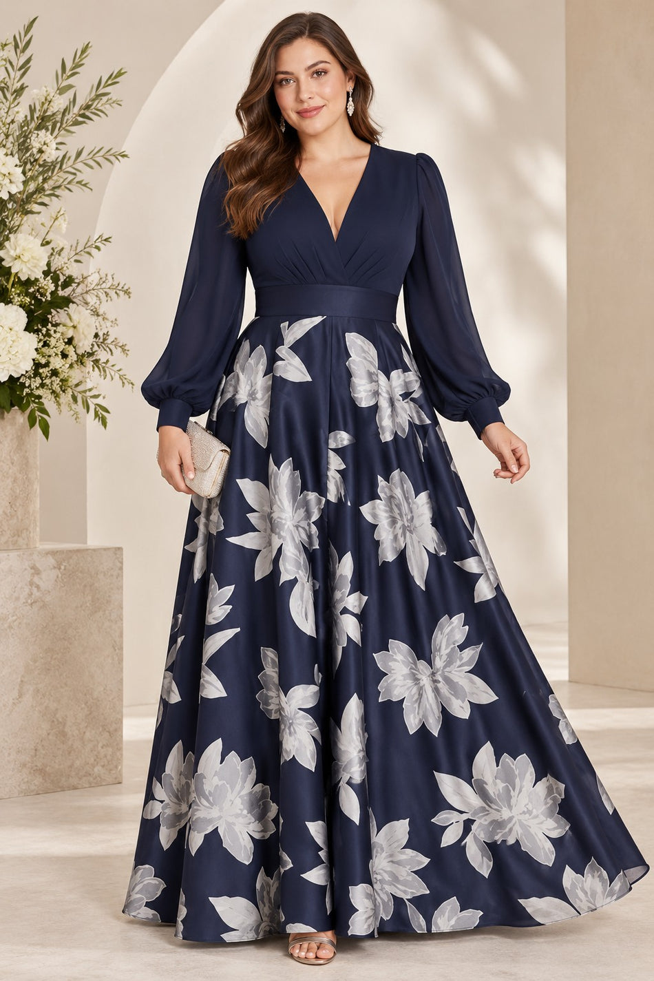 Plus size woman wearing a navy floor-length evening dress with long sleeves, V-neckline, defined waist and silver-white floral skirt.