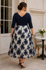 Back view of a plus size navy and ivory floral midi dress with V-shaped back, three-quarter sleeves, defined waist and full A-line skirt.
