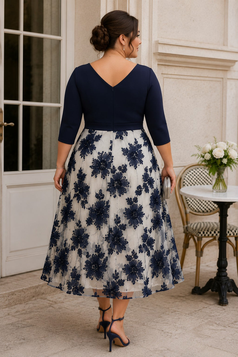Back view of a plus size navy and ivory floral midi dress with V-shaped back, three-quarter sleeves, defined waist and full A-line skirt.