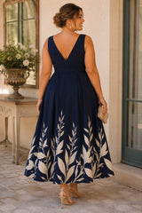 Back view of a plus size navy floral wedding guest midi dress featuring a V-back, defined waistband and flowing floral A-line midi skirt.