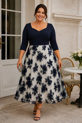 Plus size woman wearing a navy and ivory floral midi dress with three-quarter sleeves, shaped neckline, defined waist and full A-line skirt.