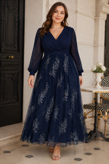 Plus size woman wearing a navy floral evening dress with wrap V-neck bodice, sheer long sleeves, defined waist and flowing maxi skirt.