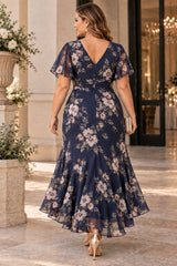 Back view of a plus size navy floral wedding guest dress with V-shaped neckline, flutter sleeves and flowing midaxi skirt.
