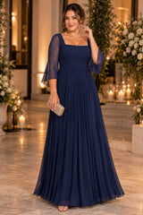 Woman wearing a navy blue plus size formal dress with a square neckline, sheer flutter sleeves and flowing pleated skirt.