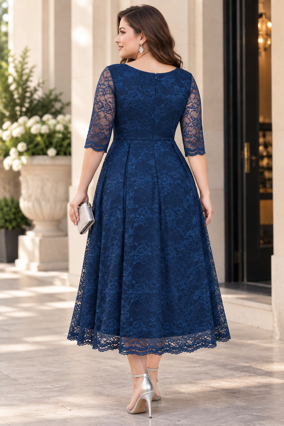 Back view of a plus size navy lace midi cocktail dress with elbow-length lace sleeves, defined waist and full A-line skirt.