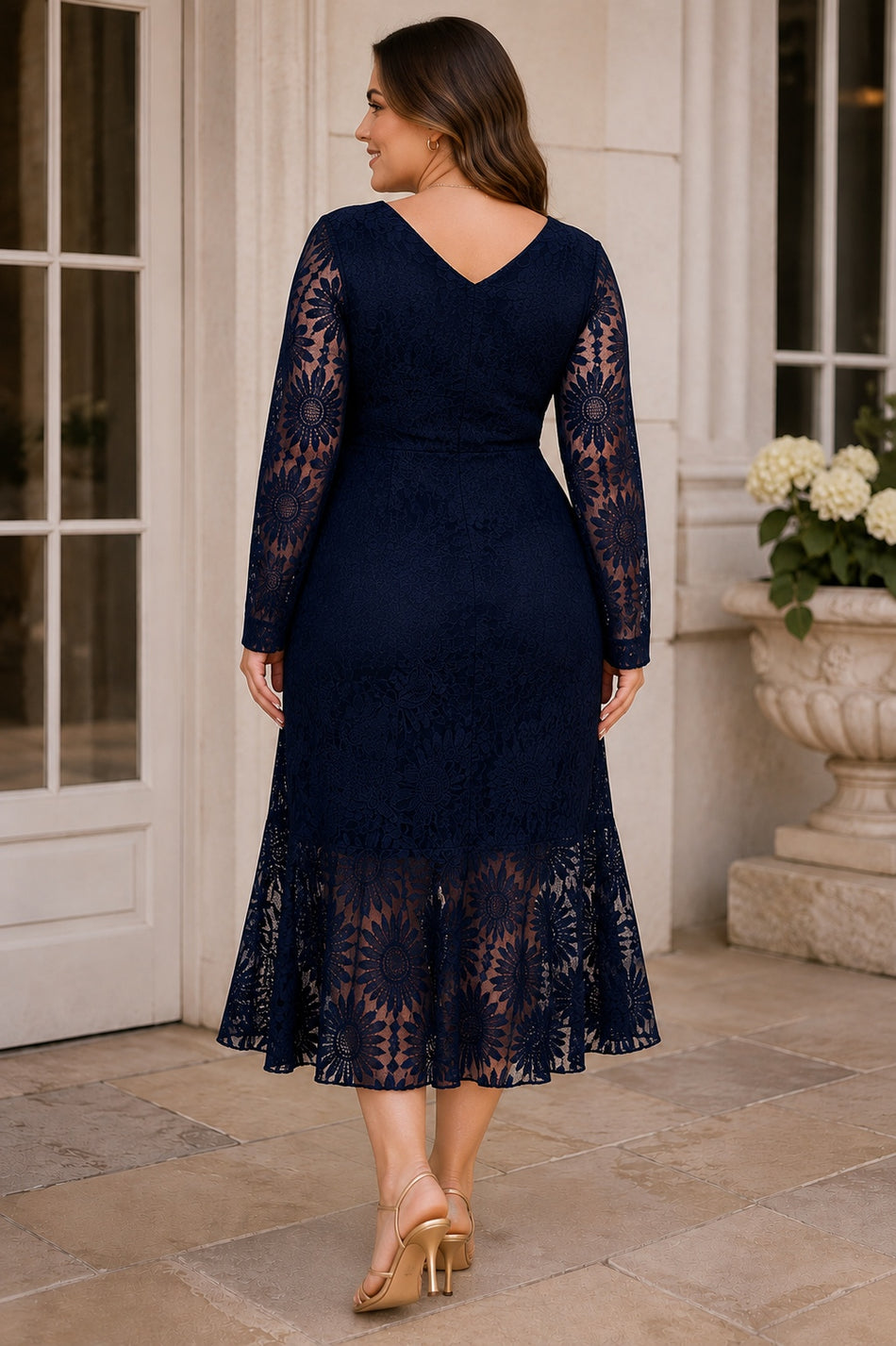 Back view of navy plus size lace wedding guest dress with V-shaped neckline, sheer long sleeves and flared lace hem.