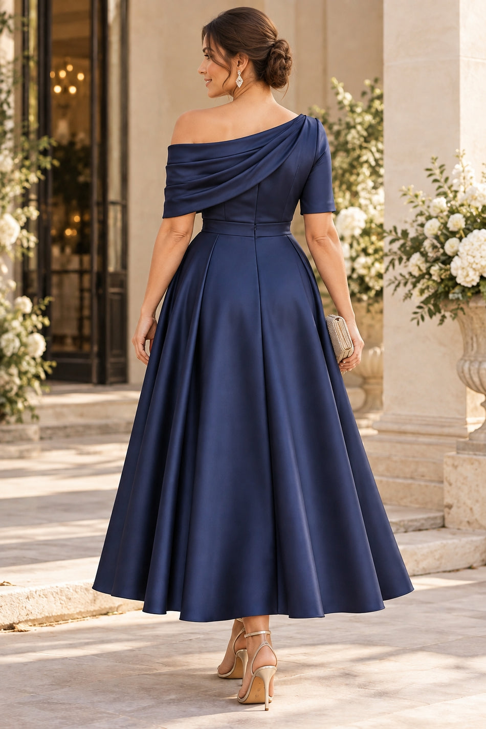Back view of a navy satin midi formal dress with an asymmetric off-shoulder neckline, defined waist and A-line skirt.