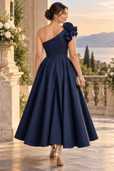 Back view of a midnight navy one shoulder cocktail midi dress with asymmetric neckline, defined waist and full skirt.