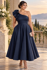 Plus size woman wearing a midnight navy one shoulder cocktail midi dress with statement shoulder detail and full A-line skirt.
