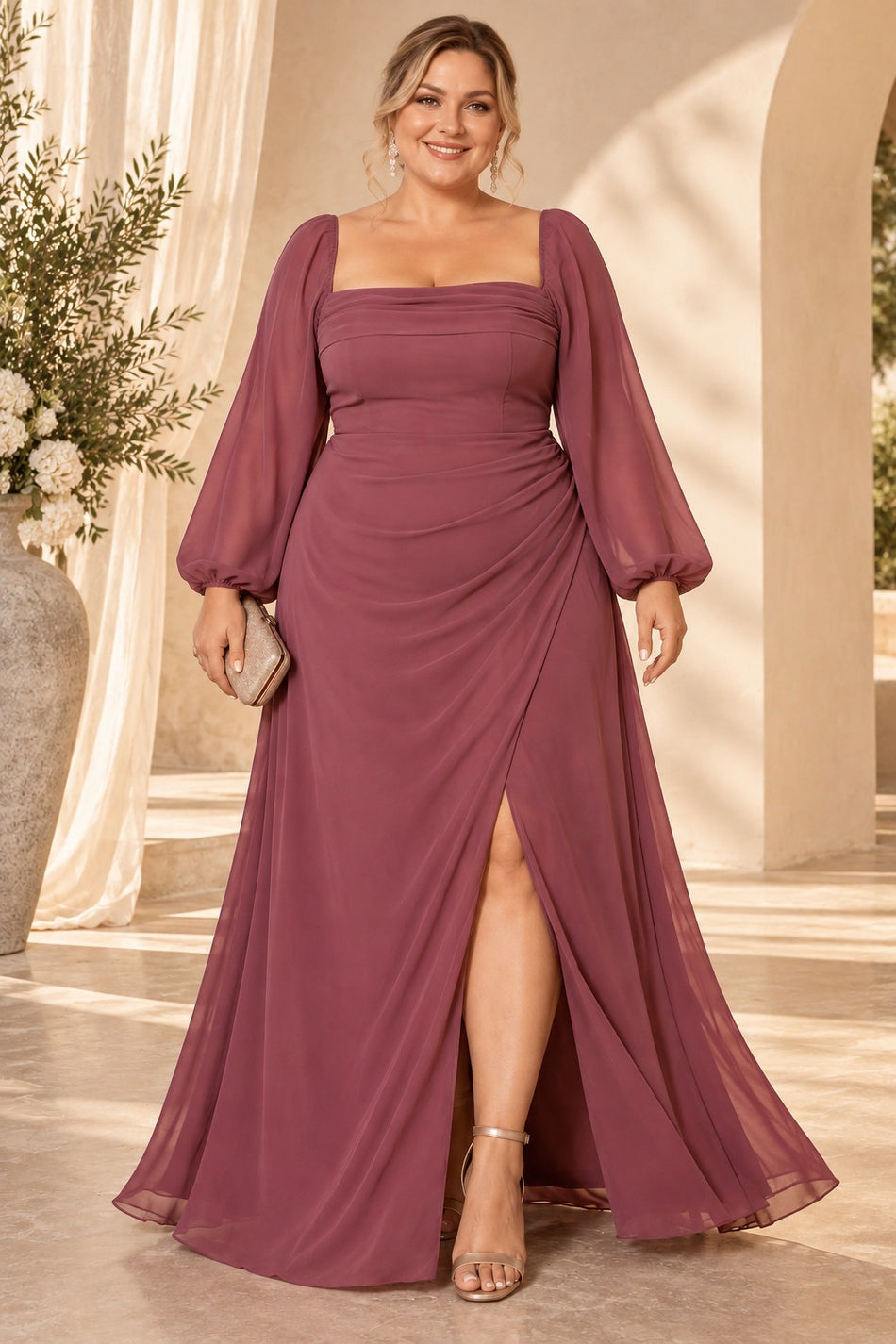 Plus size woman wearing a dusty rose pink evening maxi dress with square neckline, long sheer sleeves, draped waist and front split.