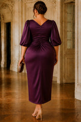 Back view of the Elise plum plus size cocktail midi dress featuring a V-back neckline, gathered waist detail, elbow-length puff sleeves and midi-length skirt.
