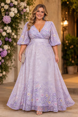 Plus size woman wearing a purple floral maxi wedding guest dress with V-neck bodice, elbow-length sleeves and full A-line skirt.