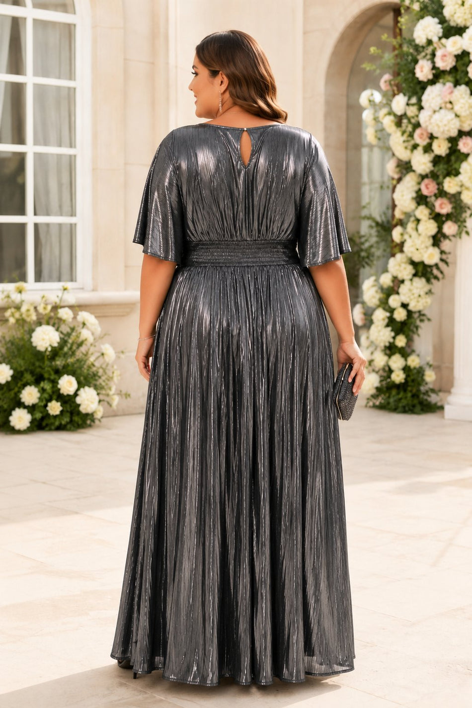 Back view of a silver metallic pleated wedding guest maxi dress with dolman sleeves and keyhole back detail.