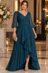 Plus size woman wearing a teal maxi evening dress with pleated V-neck bodice, sheer three-quarter sleeves and cascading front skirt.