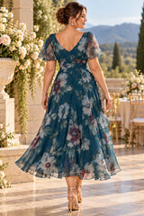 Back view of plus size teal floral wedding guest dress with flutter sleeves and flowing skirt