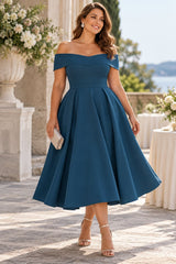 Woman wearing a teal off shoulder cocktail midi dress with a sweetheart neckline, fitted waist and full A-line skirt.