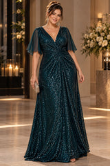 Woman wearing a plus size dark teal sequin evening maxi dress with a deep V-neckline, sheer flutter sleeves and gathered waist.