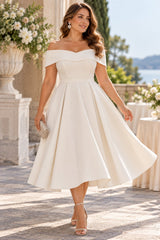 Woman wearing a white off shoulder cocktail midi dress with a defined waist and full structured A-line skirt.